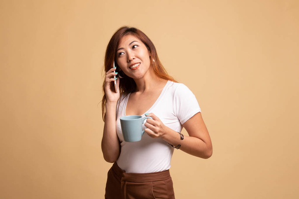 Young Asian woman with mobile phone and coffee cup. - Foto, immagini