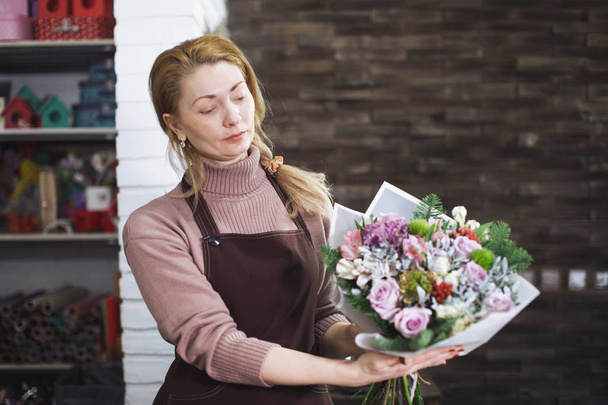 Krásná květinová žena středního věku v zástěře sbírá kytici. - Fotografie, Obrázek