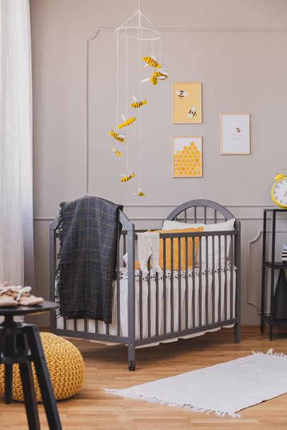 Installation with yellow and black bees above grey wooden crib with blanket and pillow - Foto, Imagem