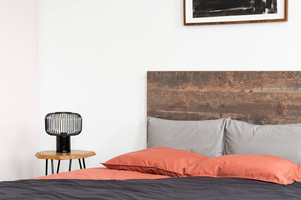 木製ヘッドボード、サンゴシート、黒い工業用ラム付きベッド - 写真・画像