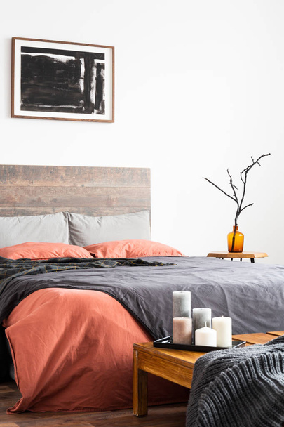 Vertical shot of wooden bed with linen bedclothes, artwork and o - 写真・画像