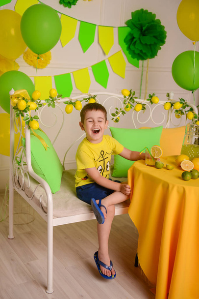 naughty boy drinks citrus lemonade from a straw and laughs - Fotografie, Obrázek