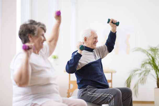 Elderly man exercising with his friend during pilates for seniors - Foto, imagen
