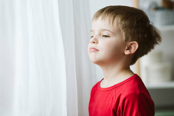 Autistic boy standing by the window at home - Foto, Imagem