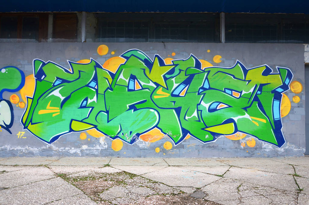 Θραύσμα από χρωματιστούς πίνακες γκράφιτι του δρόμου με καμπύλες και σκίαση. Φόντο της κουλτούρας της σύγχρονης τέχνης της νεολαίας. Πράσινα και κίτρινα χρώματα - Φωτογραφία, εικόνα
