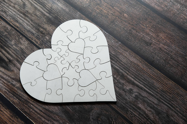Love shape white puzzle on top of wooden table. Love and caring conceptual. - Foto, Imagem