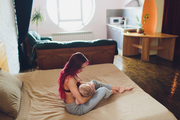 Fiatal anya szoptatja újszülött kisfiát otthon. - Fotó, kép