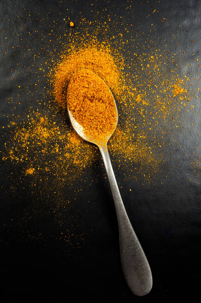 Top view of a spoon with curry powder isolated on black - Photo, Image