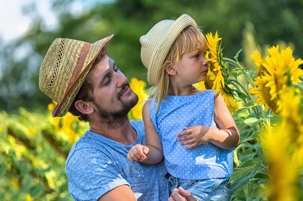 Father and daughter are smelling sunflower - Fotó, kép
