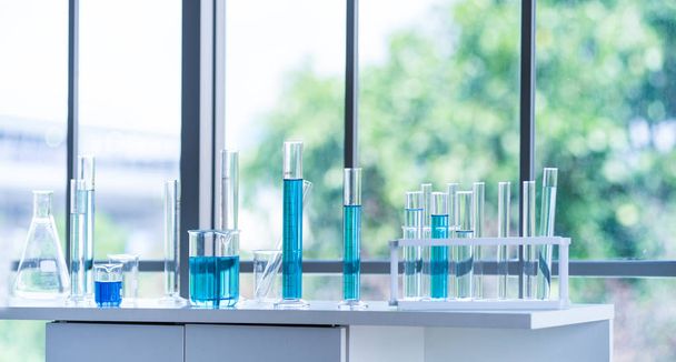 Vorbereitung von Laborgeräten wie Glaswaren, Röhren mit blauer Flüssigkeit auf dem weißen Tisch. das chemische Experiment in der wissenschaftlichen Forschung - Foto, Bild