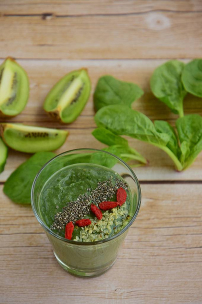 Green smoothie with spinach, kiwi, cucumber, spirulina, goji berry, chia seed and hemp seeds - Photo, Image