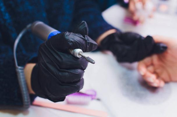 Hands in gloves cares about mans hand nails. Manicure beauty salon. - Φωτογραφία, εικόνα