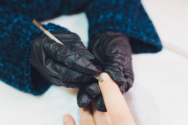 Hands in gloves cares about mans hand nails. Manicure beauty salon. - Photo, image