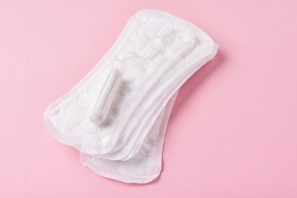 Санитарная прокладка и менструальный тампон на розовом фоне
 - Фото, изображение