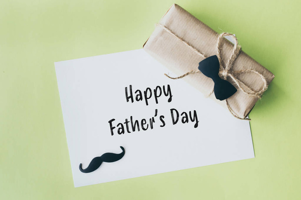 La fête des pères. Emballage cadeau enveloppé de papier et corde avec un nœud papillon décoratif sur fond vert
 - Photo, image