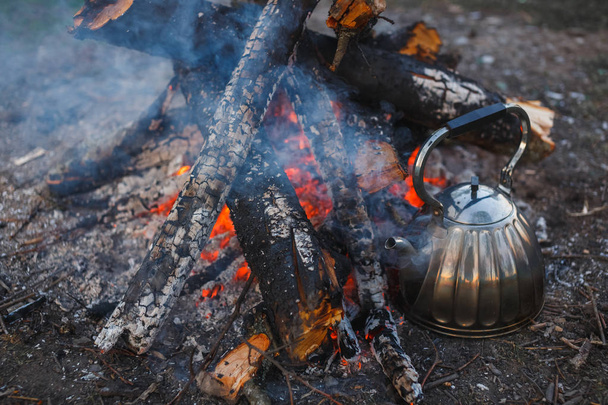 A teapot with tea stands by the fire. Evening photography - Photo, image