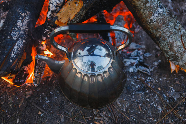 A teapot with tea stands by the fire. Evening photography - Foto, imagen