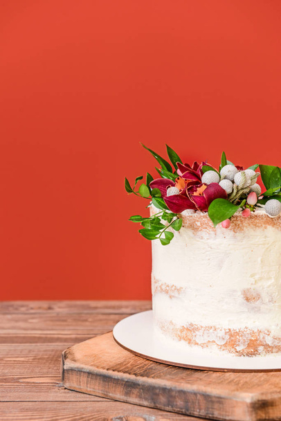 Sweet cake with floral decor on table against color background - Φωτογραφία, εικόνα