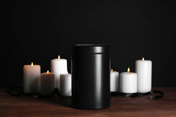 Mortuary urn with burning candles on table against dark background - Fotó, kép