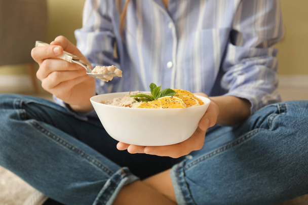 Young woman eating tasty sweet oatmeal at home - Foto, afbeelding