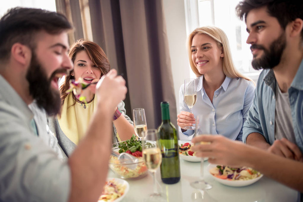 Conceito de lazer, alimentação, comida e bebidas, pessoas e feriados - amigos sorridentes almoçando e bebendo vinho em casa
. - Foto, Imagem