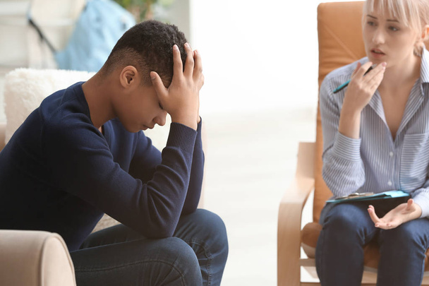 Vrouwelijke psycholoog werken met depressieve tiener jongen in Office - Foto, afbeelding