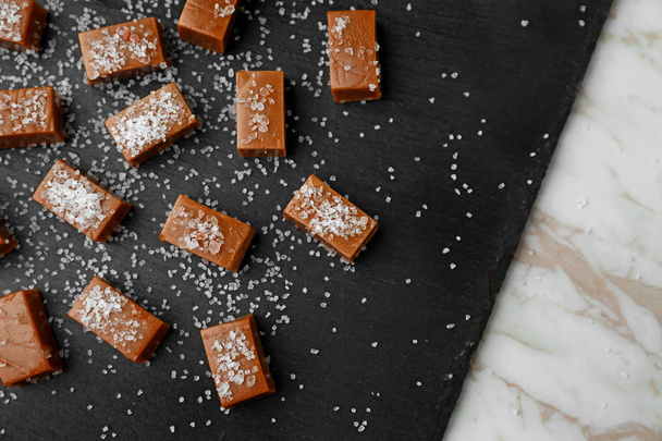Tasty salted caramel candies on slate plate - Foto, Bild