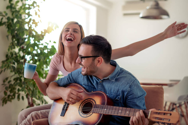 Pohledný muž hrát nějakou hudbu na kytaru se svou přítelkyní. - Fotografie, Obrázek