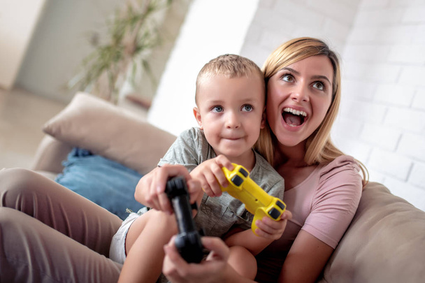 Excited mother and son playing video games together. - Photo, Image