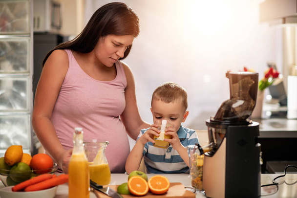 Familia hacer jugo de naranja fresca en su cocina, pasando un buen rato juntos. - Foto, imagen