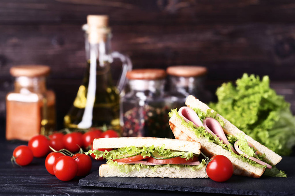 Sandwiches con jamón, queso y verduras sobre mesa de madera negra
 - Foto, imagen