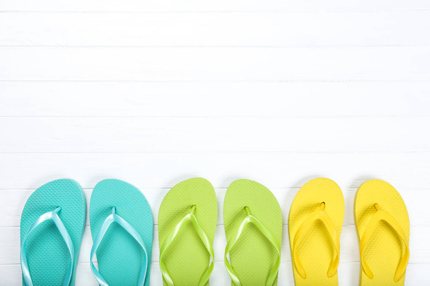 Pairs of colorful flip flops on white wooden table - Foto, afbeelding