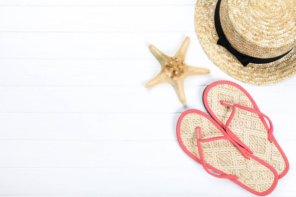Pair of flip flops with starfish and hat on white wooden table - Photo, Image