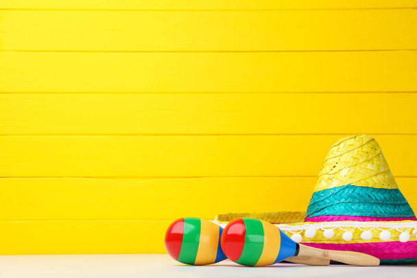 Mexican hat and maracas on yellow background - Photo, image