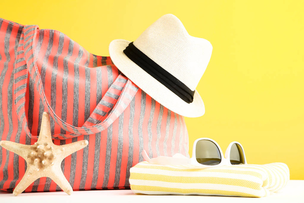 黄色の背景に帽子とタオル付きのサマーバッグ - 写真・画像