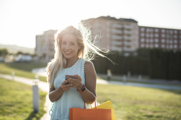Woman in park looking smartphone after shopping,  - Foto, Imagen