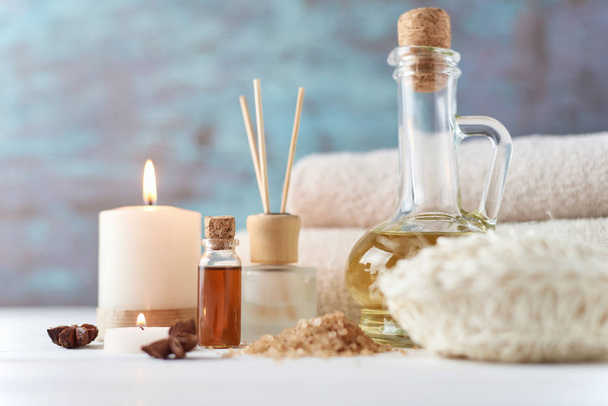 Towels, candle and massage oil on white table - 写真・画像
