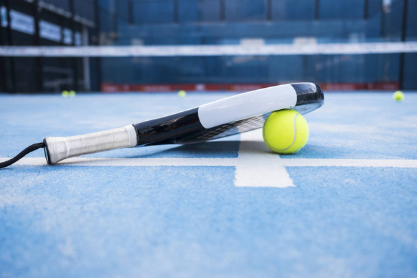  Racket and padel balls on the blue court. - Foto, afbeelding
