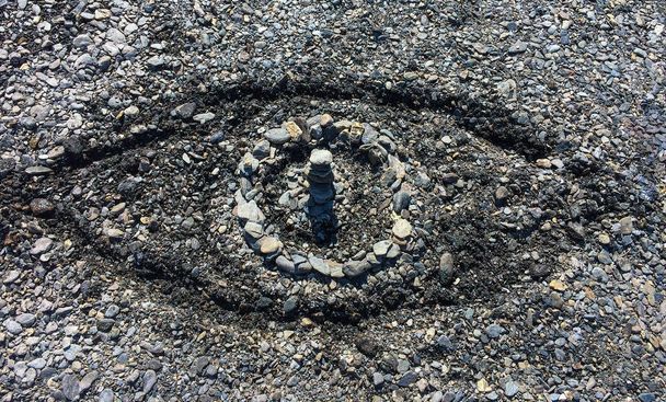 Symbolisch oog gemaakt van stenen en gesneden zand op een zomer kiezelstrand-concept van grote broer, alomtegenwoordigheid van God of openbare surveillance - Foto, afbeelding