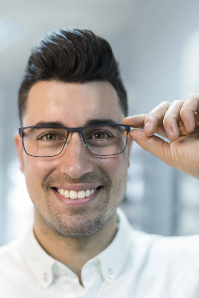 Handsome man trying on glasses in optical eye store - Fotoğraf, Görsel