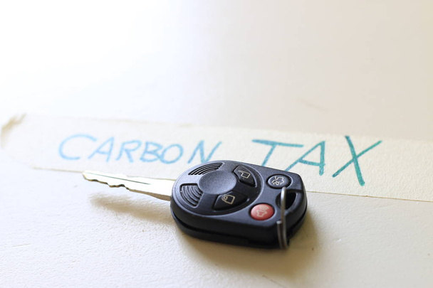 炭素税と書いてあるメモの横にある車のキー。運転コストを増やす、または炭素税の問題を増やすという概念. - 写真・画像
