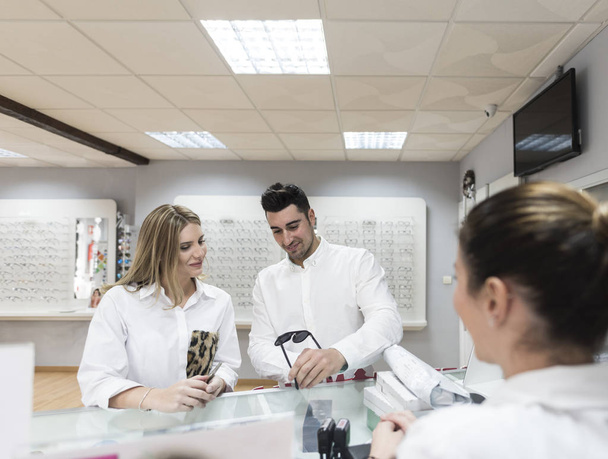 young attractive Couple selecting and buying eyeglasses in store - Foto, Bild