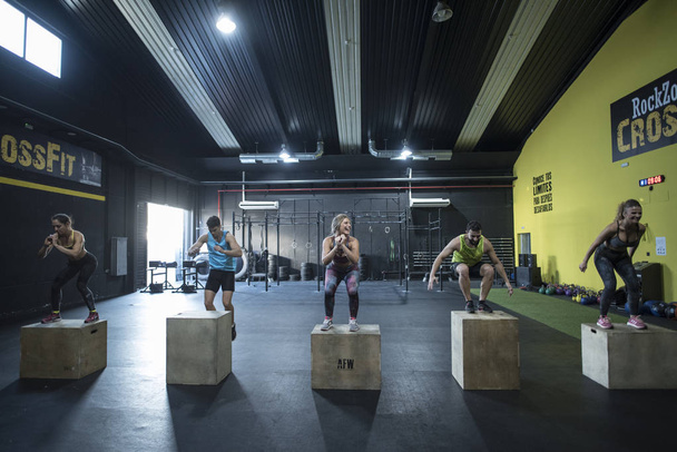 People training in crossfit class jumping on boxes - Fotó, kép