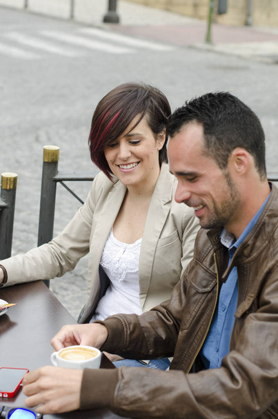 couple touching smartphone and drinking cofffee in restaurant terrace - Foto, imagen