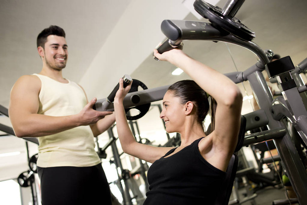 Fitness trainer helpt vrouw in borst oefeningen - Foto, afbeelding