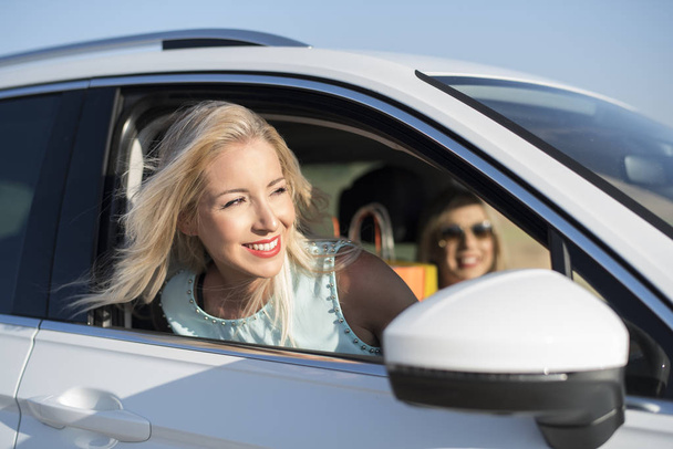 Kaksi onnellista siskoa autossa onnellinen ja hymyilee ostosten jälkeen
 - Valokuva, kuva