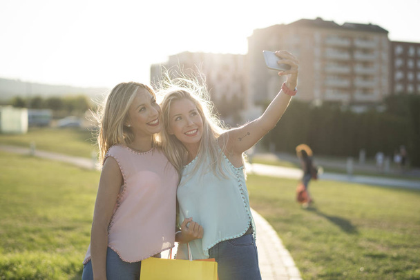 Sœurs heureuses prenant selfie après des achats dans l'image de coucher de soleil
 - Photo, image