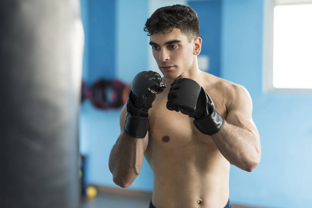 Boxer in gym training with punching bag - Valokuva, kuva