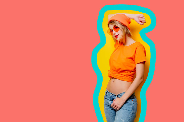 Młody styl dziewczyna z pomarańczowymi okularami na wyciągnięty koral kolor backgr - Zdjęcie, obraz
