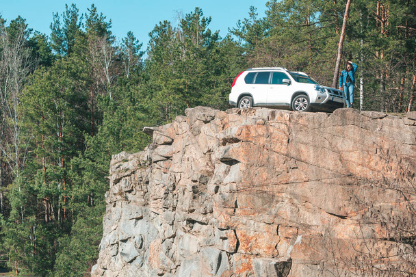young stylish woman on cliff with white suv car - Foto, afbeelding
